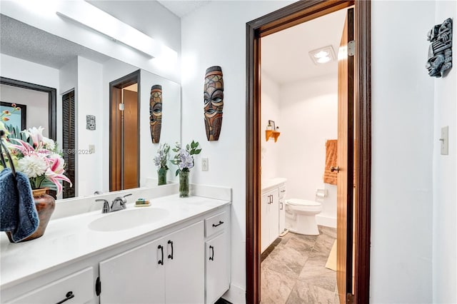 bathroom featuring toilet, a textured ceiling, and vanity