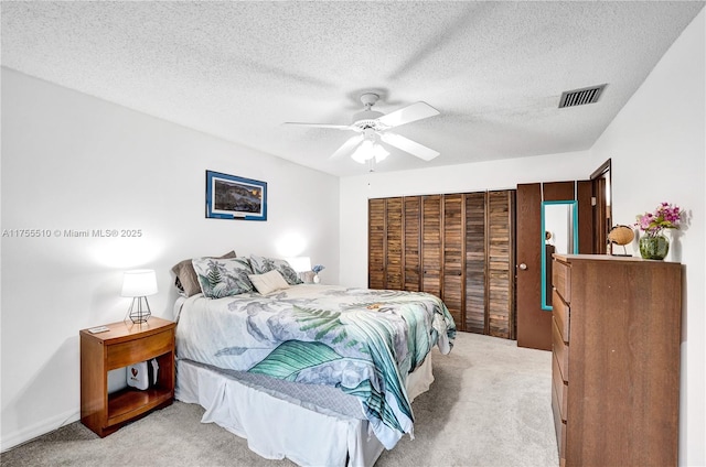 bedroom with light carpet, ceiling fan, visible vents, and a textured ceiling