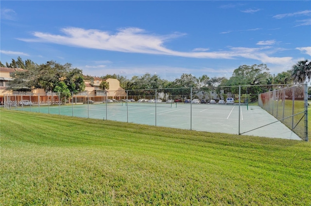 view of sport court with a lawn and fence