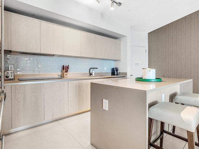 kitchen with a center island, light countertops, backsplash, a sink, and a kitchen breakfast bar