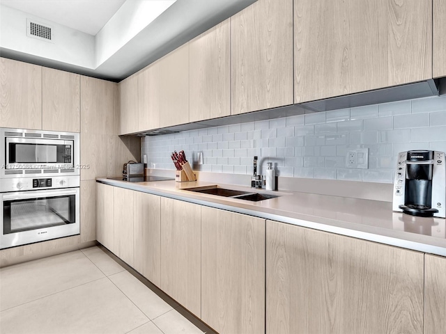 kitchen with appliances with stainless steel finishes, tasteful backsplash, visible vents, and light brown cabinetry