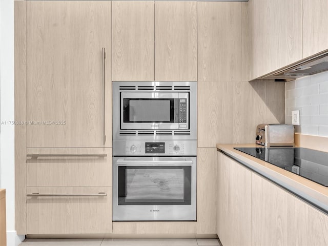 kitchen featuring stainless steel appliances, modern cabinets, light brown cabinets, and decorative backsplash