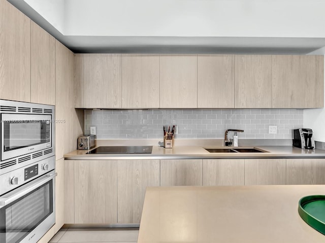 kitchen featuring light brown cabinetry, appliances with stainless steel finishes, a sink, and light countertops