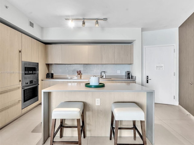 kitchen featuring appliances with stainless steel finishes, a breakfast bar, and light brown cabinets