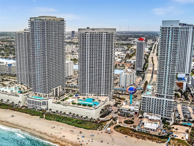 drone / aerial view featuring a water view, a view of the beach, and a city view