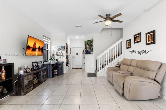 living room featuring light tile patterned floors, ceiling fan, and stairs