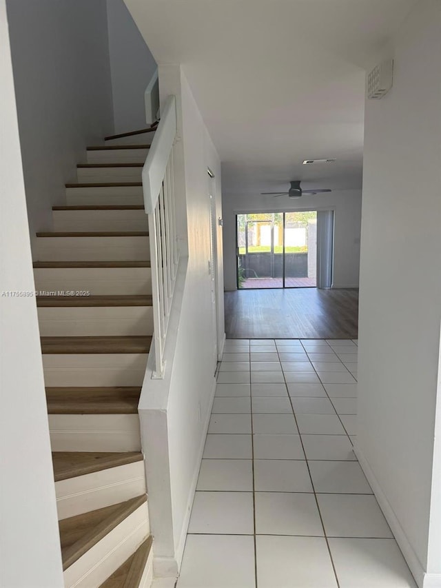 corridor featuring tile patterned floors, baseboards, and stairs