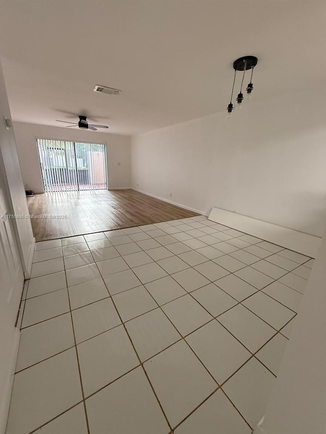 tiled empty room featuring visible vents and ceiling fan