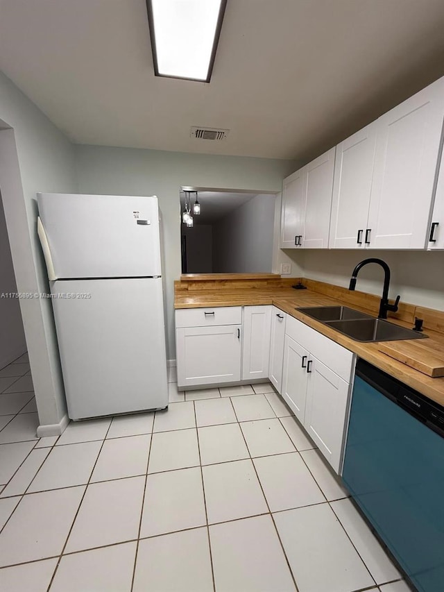 kitchen featuring visible vents, a sink, freestanding refrigerator, dishwashing machine, and wooden counters