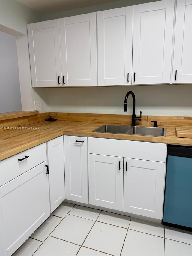 kitchen featuring a sink, dishwasher, light tile patterned flooring, and butcher block countertops