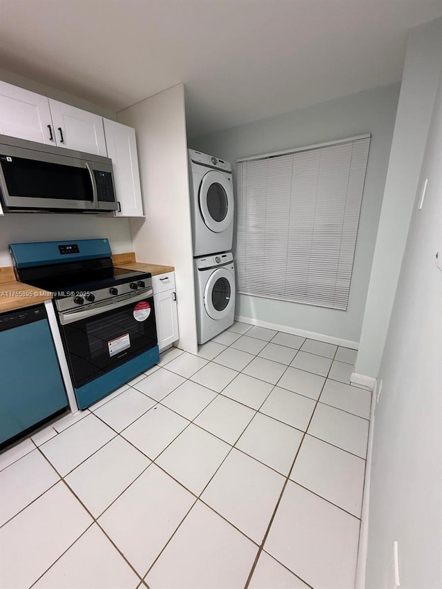 kitchen featuring wood counters, white cabinetry, stainless steel appliances, stacked washer / dryer, and baseboards