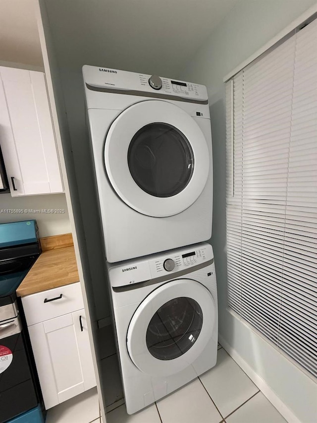 clothes washing area featuring light tile patterned flooring, laundry area, and stacked washer and clothes dryer