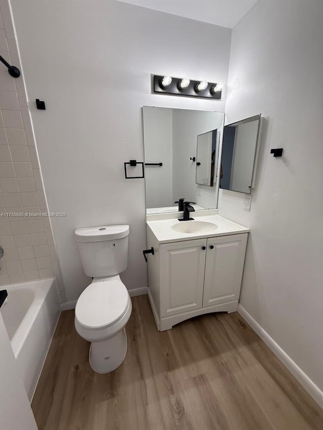 bathroom with vanity, toilet, wood finished floors, and baseboards