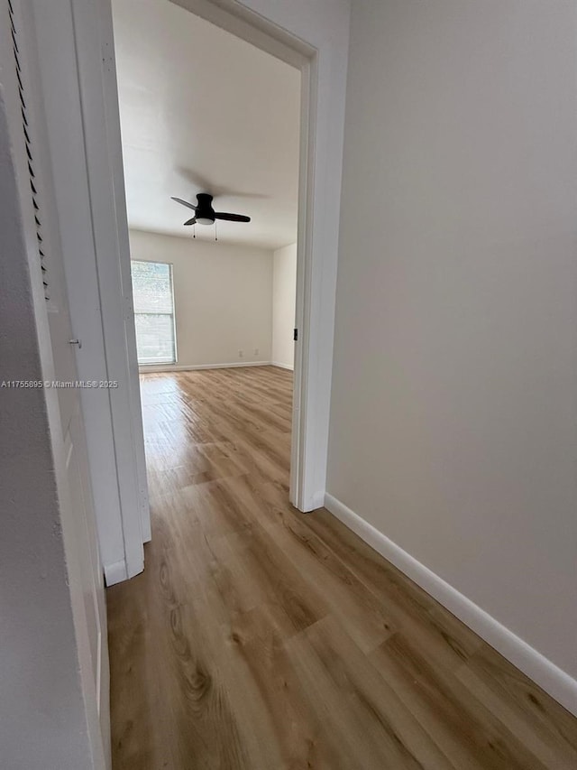 hallway featuring wood finished floors and baseboards