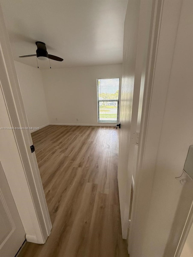 empty room with wood finished floors, baseboards, and ceiling fan