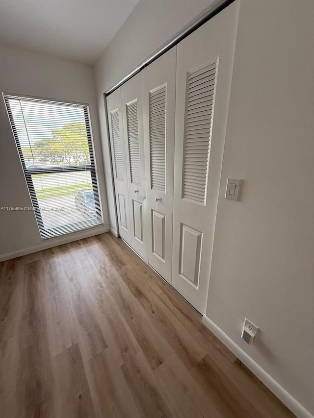 unfurnished bedroom featuring a closet, baseboards, and light wood finished floors