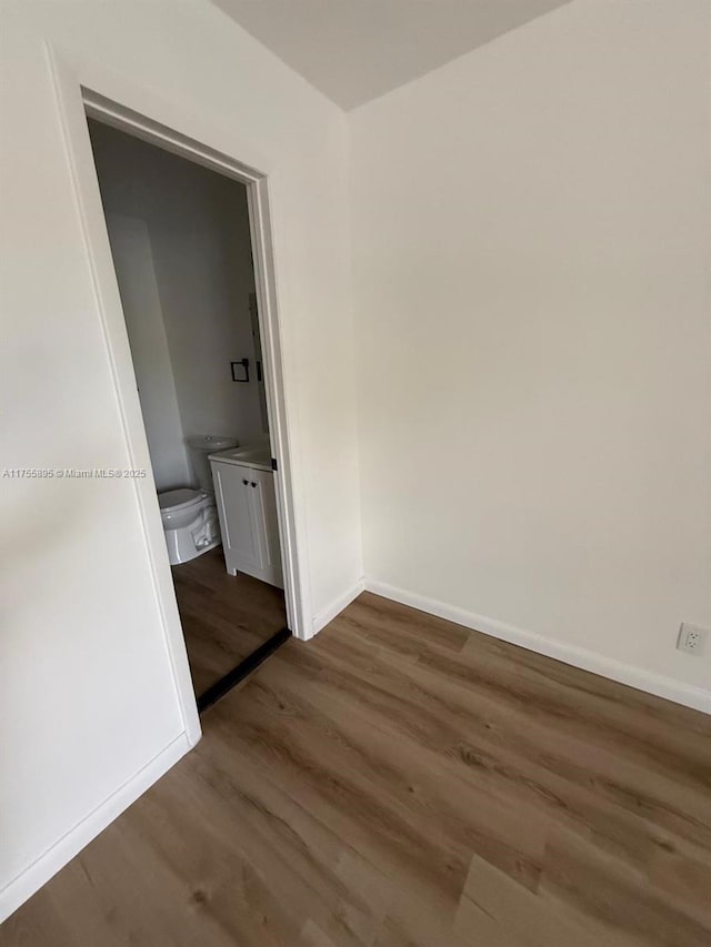 spare room with baseboards and wood finished floors