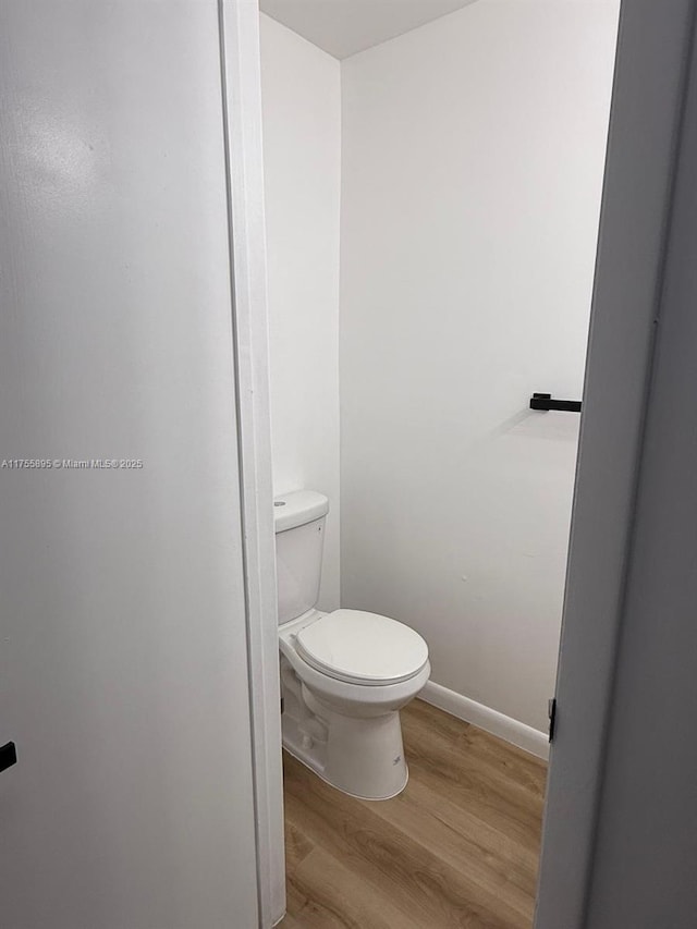 bathroom featuring toilet, baseboards, and wood finished floors