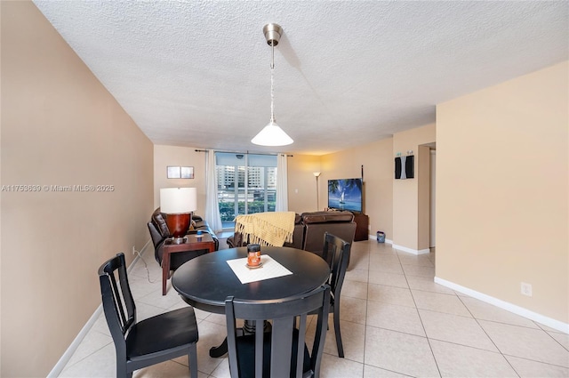 dining space featuring light tile patterned flooring, a textured ceiling, and baseboards