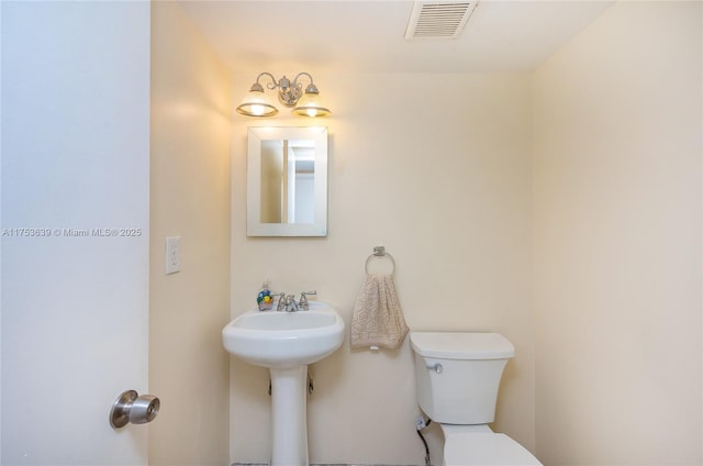 bathroom featuring toilet, visible vents, and a sink