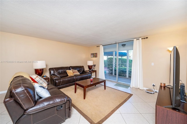 living room featuring light tile patterned floors, a textured ceiling, a wall of windows, and baseboards