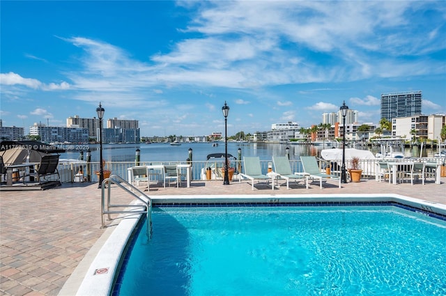 pool featuring a view of city, a patio area, and a water view