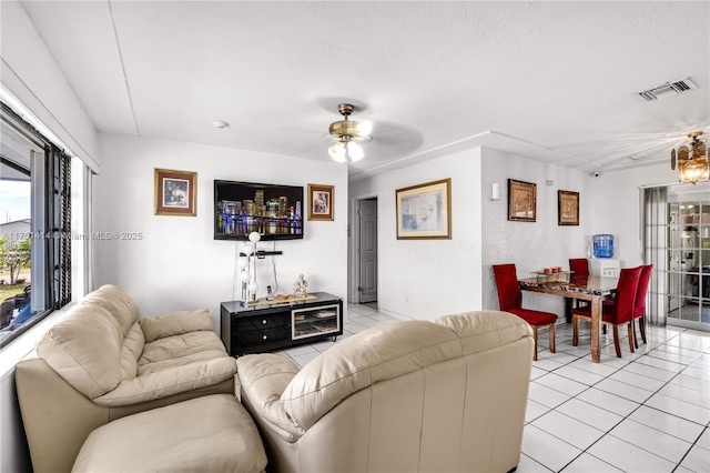 living room with a ceiling fan, visible vents, a textured ceiling, and light tile patterned flooring