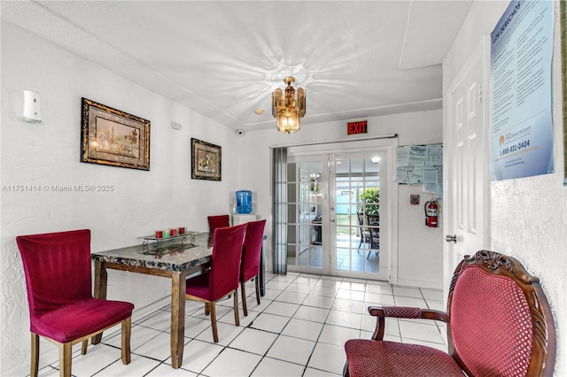 dining area featuring light tile patterned floors, a textured wall, a notable chandelier, and french doors