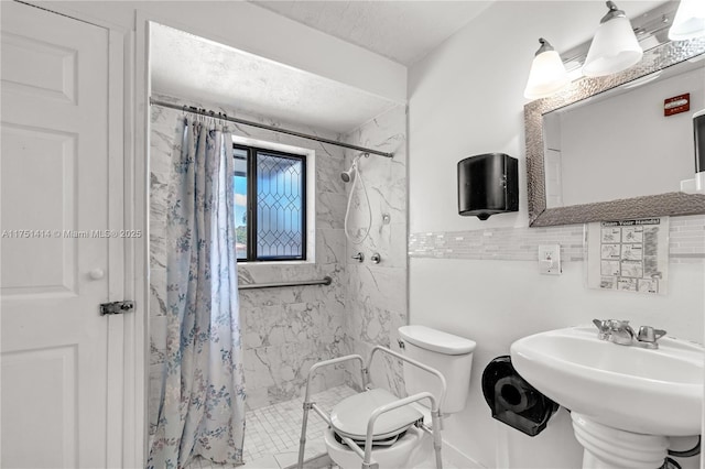 bathroom with a stall shower, a sink, a textured ceiling, and toilet