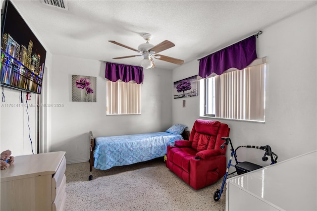 bedroom featuring ceiling fan, visible vents, a textured ceiling, and speckled floor