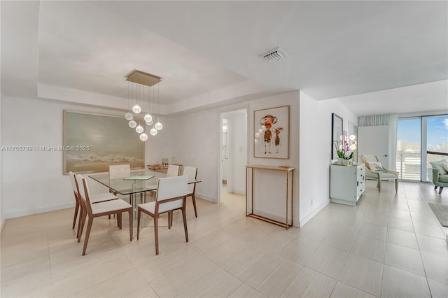 dining room featuring a notable chandelier, baseboards, visible vents, and a tray ceiling