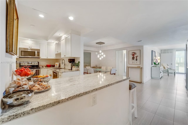 kitchen with light stone counters, recessed lighting, a sink, white cabinets, and appliances with stainless steel finishes