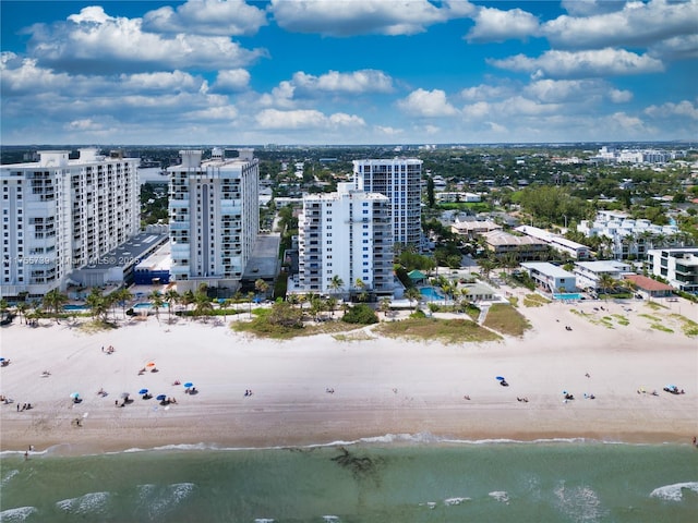 drone / aerial view with a water view, a view of city, and a beach view