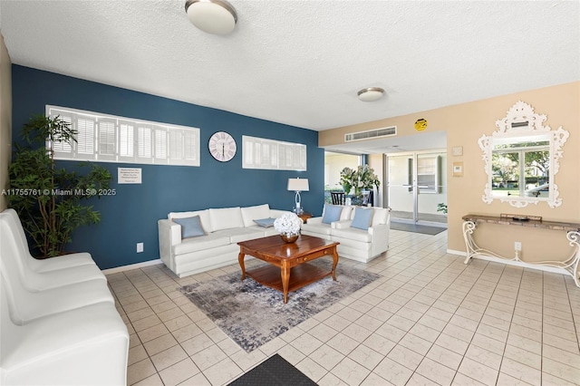 tiled living area featuring visible vents, baseboards, and a textured ceiling