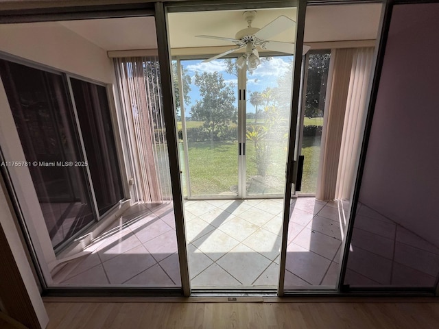 entryway with ceiling fan, a wall of windows, and wood finished floors