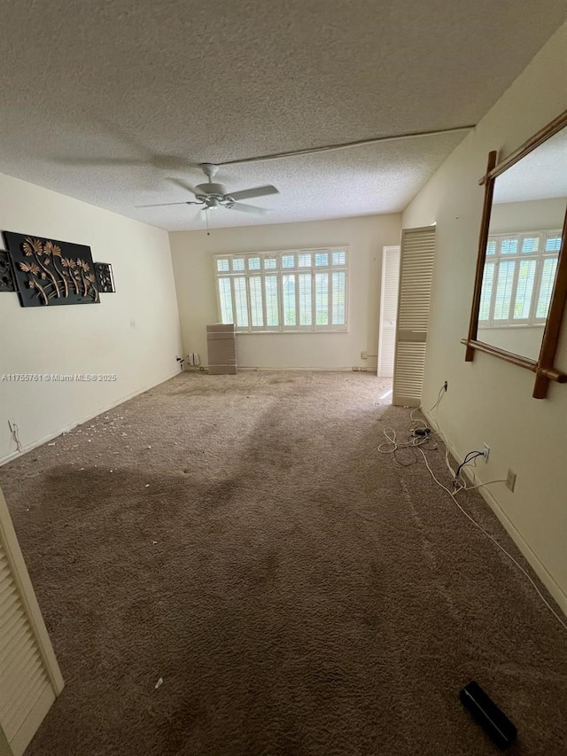 unfurnished living room with carpet floors, a wealth of natural light, ceiling fan, and a textured ceiling