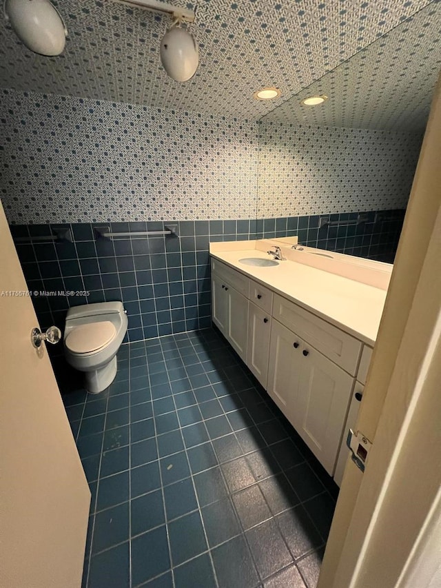 bathroom featuring toilet, tile patterned flooring, tile walls, and vanity