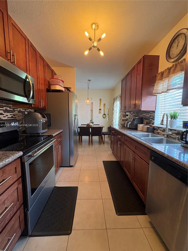 kitchen featuring backsplash, appliances with stainless steel finishes, light tile patterned flooring, a sink, and a chandelier