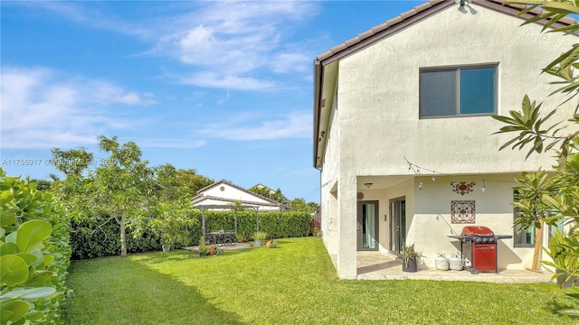 back of property featuring a tiled roof, fence, a yard, a patio area, and stucco siding