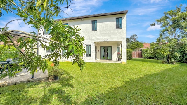 back of house featuring a yard, french doors, fence, and stucco siding