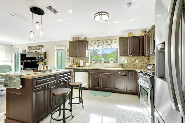 kitchen with tasteful backsplash, visible vents, appliances with stainless steel finishes, dark brown cabinets, and crown molding