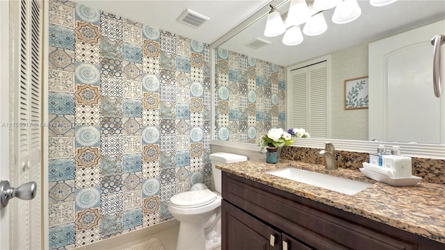 bathroom with a closet, visible vents, toilet, vanity, and a shower with curtain