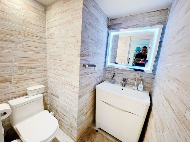 bathroom with vanity, toilet, and tile walls