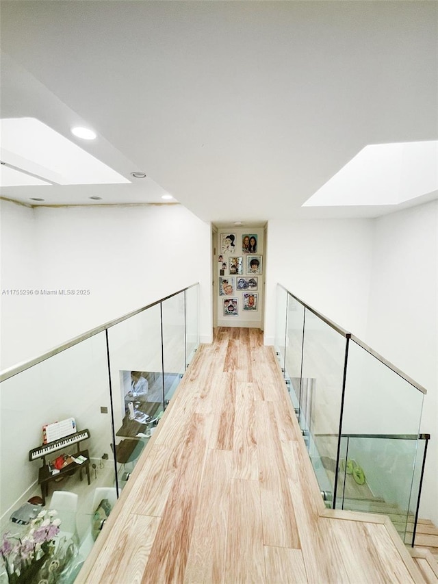 hall with recessed lighting, a skylight, and wood finished floors