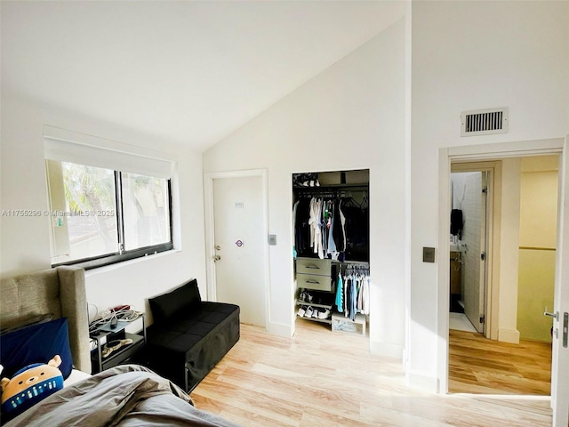 living room with light wood-style floors, visible vents, and high vaulted ceiling