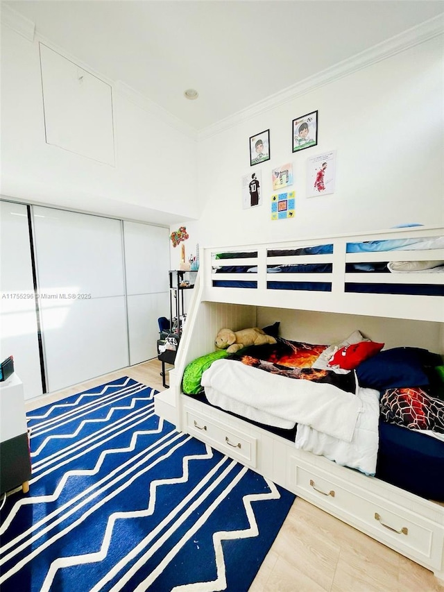 bedroom featuring ornamental molding, a closet, and wood finished floors