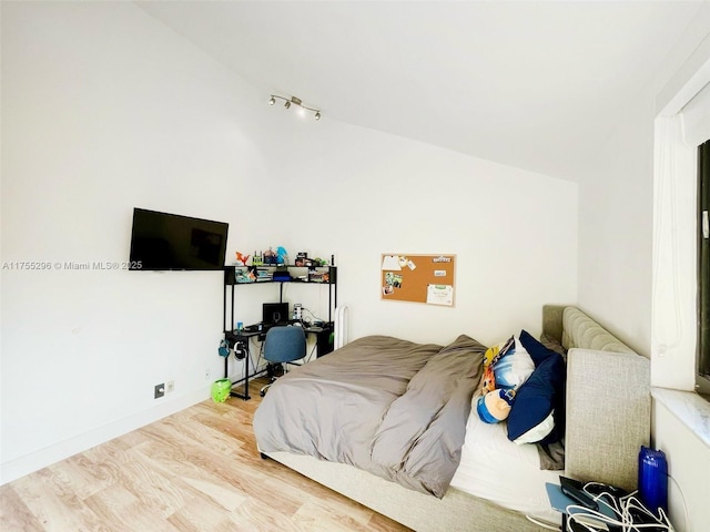 bedroom featuring vaulted ceiling, baseboards, and wood finished floors