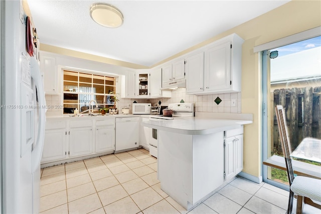 kitchen featuring light tile patterned floors, light countertops, backsplash, white appliances, and a peninsula