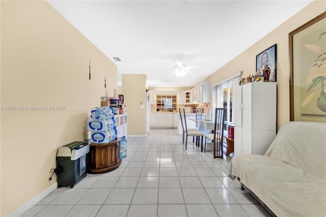 hall featuring baseboards, visible vents, and light tile patterned flooring