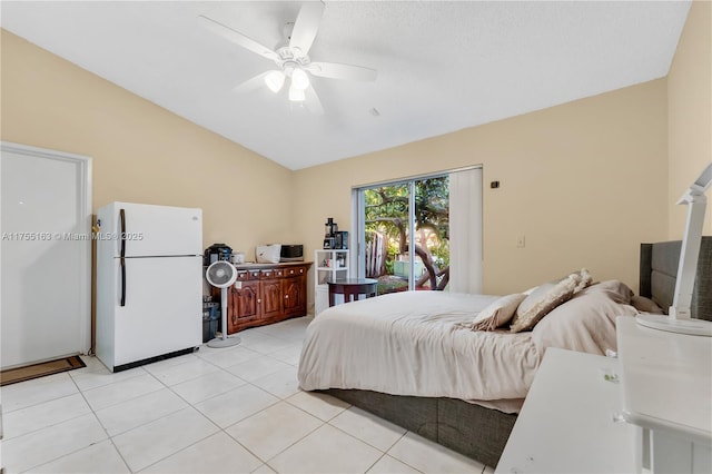 bedroom with lofted ceiling, light tile patterned floors, freestanding refrigerator, and a ceiling fan